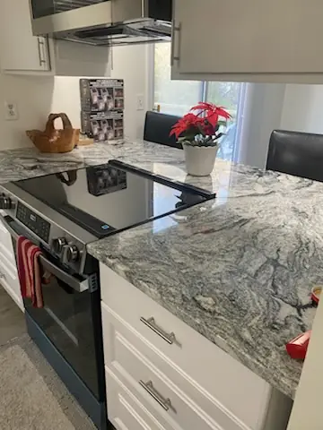 Grey marble counter beside a wiped glass cooktop