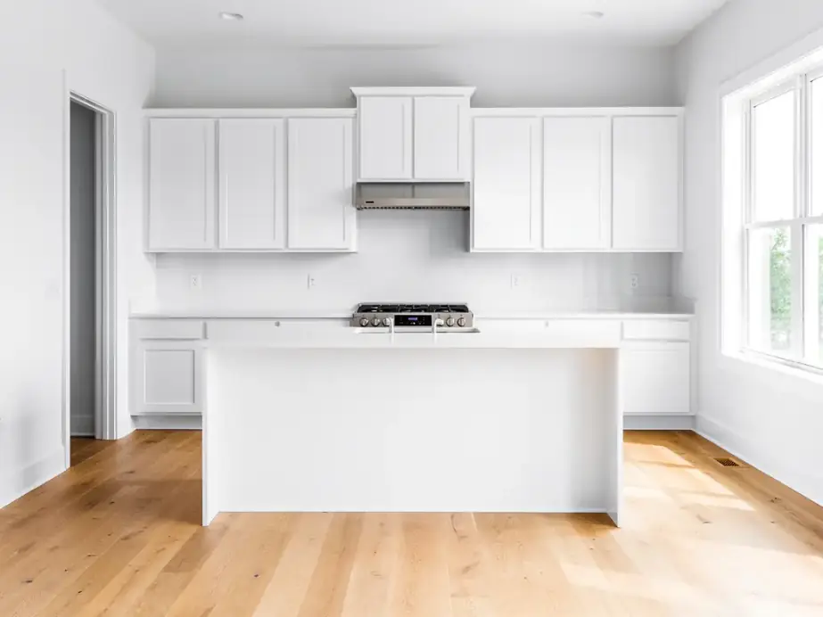 New white kitchen with bare counters and a light oak floor after the final clean